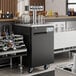 An Avantco black kegerator on a bar counter with beer taps.