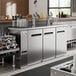 An Avantco stainless steel beer dispenser with three beer taps in a bar.