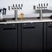 A black Avantco beer dispenser on a counter with four taps.