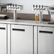 An Avantco stainless steel beer dispenser with four taps on a counter.