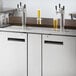 An Avantco stainless steel counter with three beer taps.