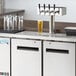 An Avantco stainless steel beer dispenser on a counter with four taps.