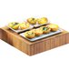 A Cal-Mil bamboo square riser with small plates of food on it.