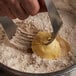 A hand using a fork to cut a piece of Crisco butter over a bowl of flour.