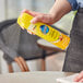 A person spraying SC Johnson Pledge orange furniture polish on a table.