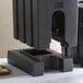 A black riser with a lid on top of it for a Cambro insulated beverage dispenser.