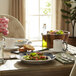 A table with a Libbey Lunar Bright White Porcelain Plate with a bowl of salad and a white mug of tea.