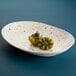An Elite Global Solutions chocolate chip oval melamine plate with a plate of fruit, including halved fruit.