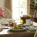 A table with a Libbey Lunar Bright White porcelain plate of salad and a white mug of tea.