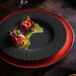 A Villeroy & Boch black shale porcelain plate with food on a table with a red and black plate.