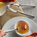 A fork and lobster claw on a plate with a Choice Cocktail Oyster Fork and Lobster Cracker Seafood Utensils set.