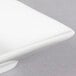 A close-up of a white square porcelain bowl on a white plate.