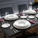 A white Villeroy & Boch bone and gold platter on a table with white plates and glasses.