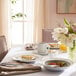 A table set with white Schonwald porcelain plates and a bowl of flowers.