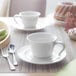 A white Villeroy & Boch Neufchatel porcelain mug on a saucer on a table.