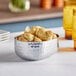 An American Metalcraft silver hammered aluminum oval bowl filled with bread sticks on a table.