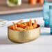An oval serving bowl of fried shrimp on a table with a blurry green background.