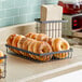 A GET Enterprises metal gray rectangular wire basket of bagels on a bakery counter.