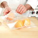 A person's hand holding two oranges in an LK Packaging plastic resealable bag.