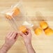 A person putting an orange in an LK Packaging plastic food bag.