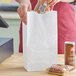 a white paper bag next to a basket of food