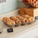 A tray of bagels in a GET Urban Renewal metal gray rectangular wire basket on a bakery counter.