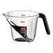 An OXO clear plastic measuring cup with a black handle.