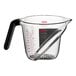 An OXO clear plastic measuring cup with a black handle.