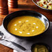 A bowl of soup with spices on a table.