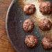 A plate of cookies with a brown cookie topped with white crystals.