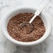 A bowl of Regal brown flax seeds with a spoon.