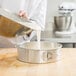 A person pouring a mixture into a Chicago Metallic aluminum springform cake pan.