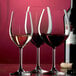 Three Stolzle Classic port wine glasses filled with red wine.