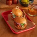 A Baker's Mark red aluminum tray with sandwiches and a drink.