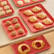 A Baker's Mark red wire in rim aluminum sheet tray of pastries on a table.