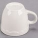 A CAC ivory espresso cup with a scalloped edge and a white handle.