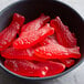 A black bowl filled with red Swedish Fish gummy candy.