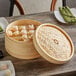 A Town bamboo steamer set with food in it on a table.