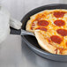 A person using a Chicago Metallic Deep Dish Pizza Pan to serve a pepperoni pizza.