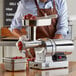 A man in an apron using a Backyard Pro electric meat grinder on a counter.