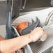 A person using a Hobart meat slicer to cut meat.