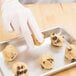 A person in gloves putting chocolate chip cookie dough on a Chicago Metallic aluminum sheet pan.