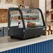 An Avantco refrigerated countertop bakery display with cakes and pastries inside.