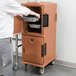 A man opening a brown Cambro food pan carrier.