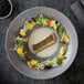 A RAK Porcelain stone gray deep coupe plate with a bowl of fish soup.