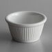 A Libbey Bedrock white fluted stoneware ramekin on a gray surface.