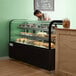 A man behind an Avantco dry bakery display case with pastries.