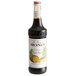 A black Monin bottle of liquid with a white label.