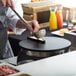 A person using the Carnival King Butane Crepe Station to cook food on a table.