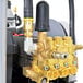 A close-up of a gold and silver Simpson pressure washer with a hose.